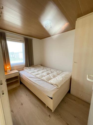 a small bedroom with a bed and a window at Chalet n°32 in Middelkerke