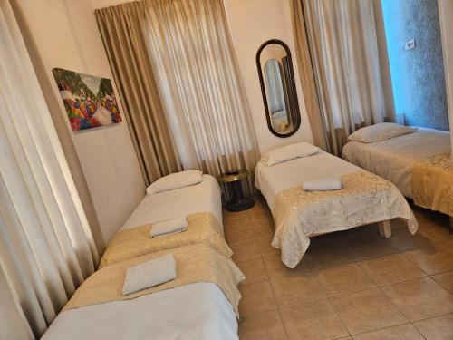 a room with three beds and a mirror at Atara Hotel in Tiberias