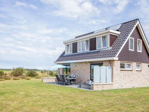 a detached house with a patio and lawn at Stylish Texel Escape with Spa in Den Burg