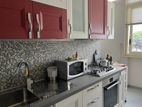 a kitchen with red cabinets and a microwave and a sink at Wave House in Palermo