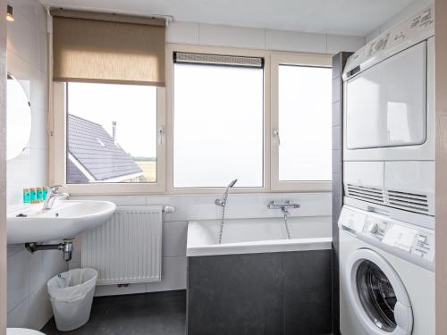 a bathroom with a sink and a washing machine at Holiday home near dunes with wellness garden in Den Burg