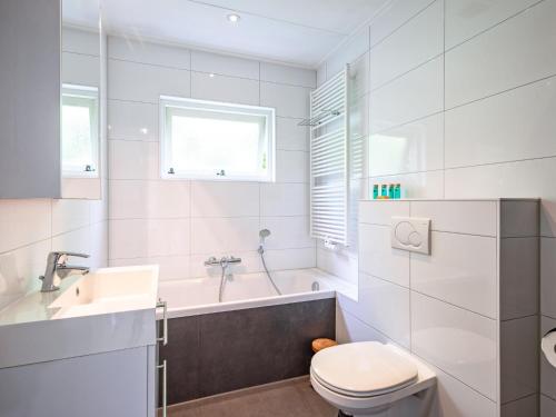 a bathroom with a tub and a toilet and a sink at Cozy holiday home in Den Burg with hot tub in Den Burg