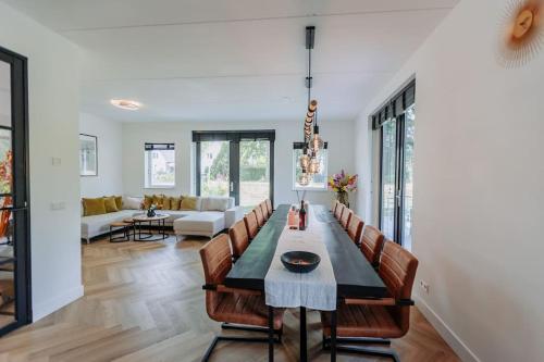Brand new luxurious 6 bedroom villa in Amsterdam في أمستردام: غرفة طعام وغرفة معيشة مع طاولة وكراسي