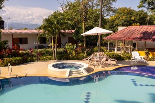 a swimming pool with two chairs and an umbrella at FINCA EL PORVENIR in Acacías