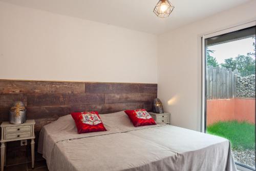 a bedroom with a bed with two red pillows at Appart - Le Tropical in Ginasservis
