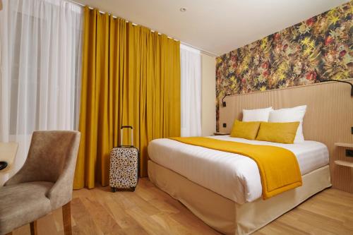 um quarto de hotel com uma cama e uma cadeira em VLH Montparnasse Eiffel em Paris