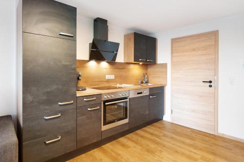 a kitchen with stainless steel appliances and wooden floors at Kaiserchalet in Höchenschwand