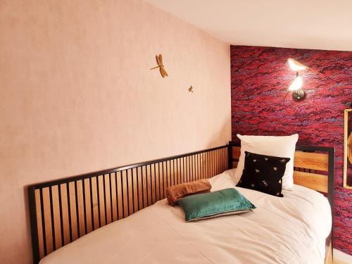 a bedroom with a bed with a red wall at Cabanes du Domaine des Fées in Dole