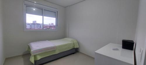 Habitación pequeña con cama y ventana en Apartamento dos ingleses, en Florianópolis