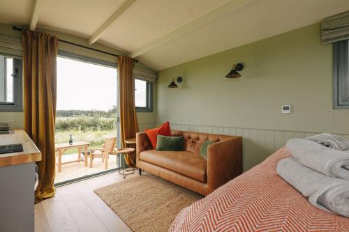 a bedroom with a bed and a couch and a window at Clover Hut - Snettisham Meadows in Snettisham