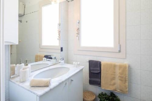a white bathroom with a sink and a mirror at [Art of Living] 100 meters from the sea. in Marina di Pietrasanta