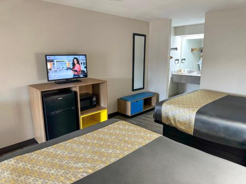 a hotel room with a bed and a flat screen tv at Days Inn & Suites by Wyndham Opelousas in Opelousas