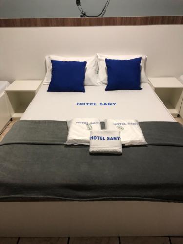 a bed with blue and white pillows on it at Hotel sany - Localizado à 5 minutos do Metrô Paulista in Sao Paulo