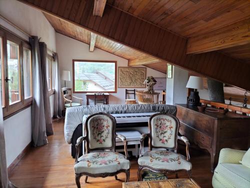een woonkamer met een piano en 2 stoelen bij Chalet Nicouski in La Salle Les Alpes