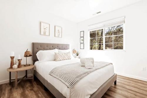 a white bedroom with a bed and a window at Brookside Cottage in Mariposa
