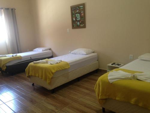 a room with two beds with yellow sheets on them at Hotel Cidade Aventura in Socorro