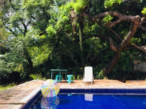 einen Pool mit zwei Stühlen, einem Tisch und einem Ball in der Unterkunft Bungalito en Cuernavaca in Cuernavaca