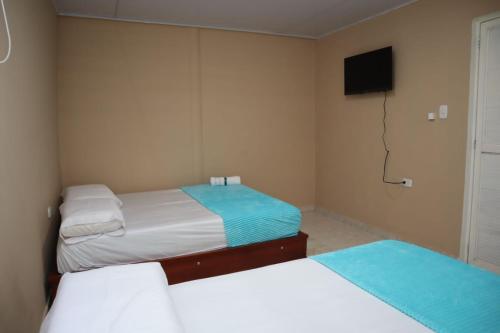 a bedroom with two beds and a tv and a television at Hotel Casa Mayorca in Maicao
