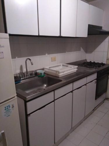 麥德林的住宿－Medellín Kimball's Appartments!，厨房配有水槽、炉灶和白色橱柜。