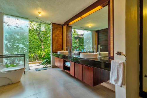 a bathroom with two sinks and a large mirror at Sri Abi Ratu Villas in Sukawati