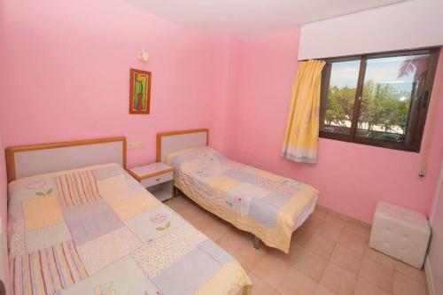 - 2 lits dans une chambre avec des murs roses et une fenêtre dans l'établissement Apart4mento marav1lloso en la playa De la fossa Paraiso Mar, à Calp