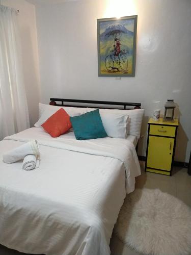 1 dormitorio con 1 cama con sábanas blancas y almohadas coloridas en Double Rooms en Nairobi