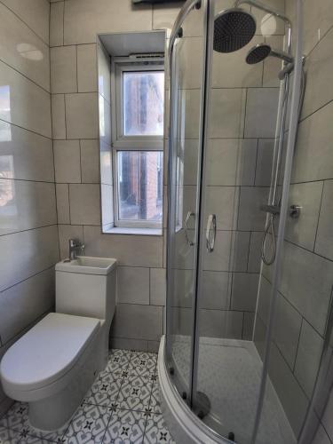 a bathroom with a toilet and a glass shower at Digbeth City Centre Apartment Sleeps 12 Opposite Coach Station in Birmingham