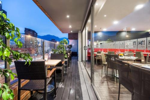 a restaurant with tables and chairs on a balcony at NH Bogota Urban 26 Royal in Bogotá