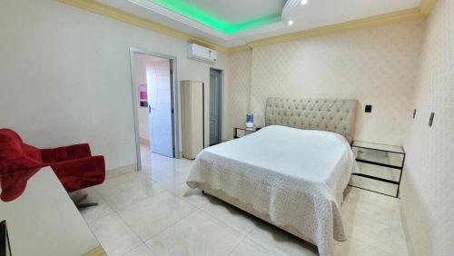 um quarto com uma cama branca e uma cadeira vermelha em Espetacular apartamento no centro em Palmas