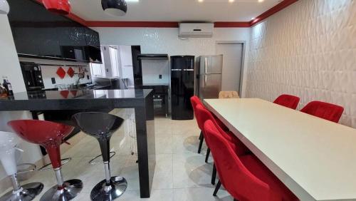 a kitchen with a white table and red chairs at Espetacular in Palmas