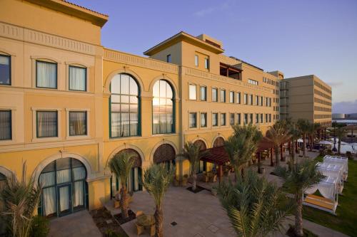 a large yellow building with palm trees in front of it at Djibouti Palace Kempinski in Djibouti