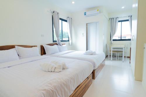 2 letti in una camera da letto con lenzuola e asciugamani bianchi di Chotika Hotel โรงแรมโชติกา ณ เชียงคาน a Chiang Khan