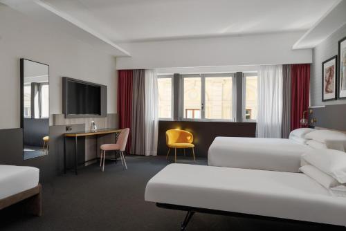 una camera d'albergo con 2 letti e una scrivania di iQ Hotel Firenze a Firenze