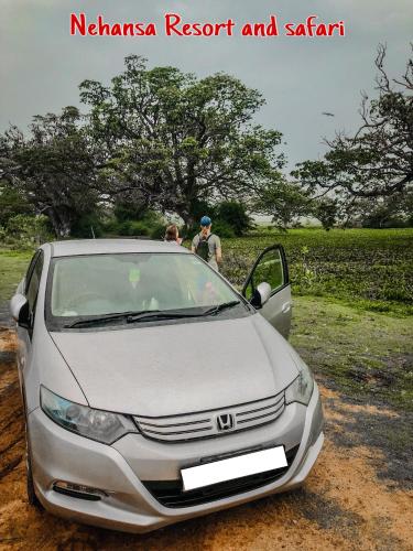 a man and a woman standing next to a silver car at Nehansa Resort and safari in Tissamaharama