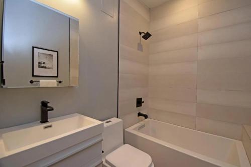 biała łazienka z wanną, toaletą i umywalką w obiekcie Cozy Apartment in Historic OTR w mieście Cincinnati