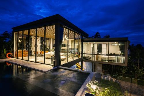 a large glass house with a pool at night at Villa Obsidian, sea view and walk to Choeng Mon beach in Choeng Mon Beach