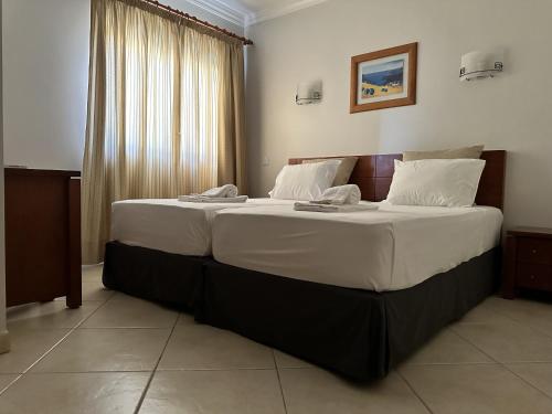 een slaapkamer met een groot bed met witte lakens bij BayView Albufeira in Albufeira