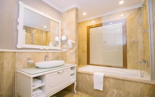 a bathroom with a sink and a tub and a mirror at Burgaz İzer Hotel in Lüleburgaz