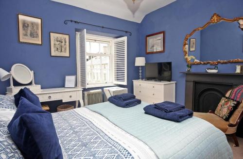 a blue bedroom with a bed and a fireplace at Awel y Mor in Beaumaris