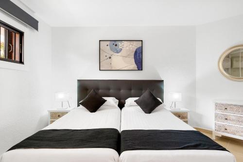 a bedroom with two beds with white walls at Paloma Beach Apartments in Los Cristianos