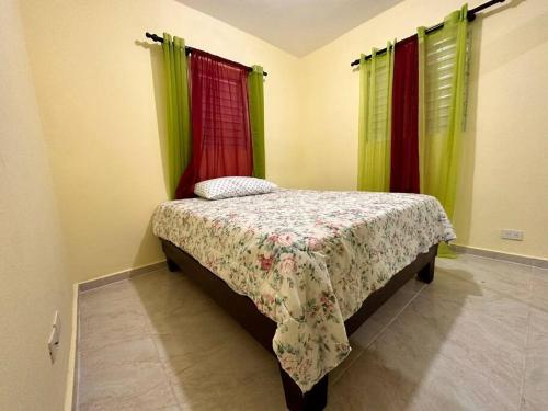 a bedroom with a bed with green and red curtains at house on the hill in Nagua