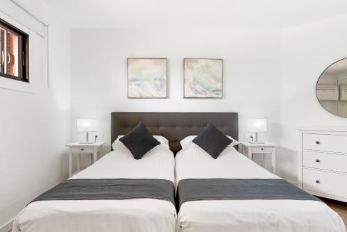 two beds in a bedroom with white walls and mirrors at Paloma Beach Apartments in Los Cristianos