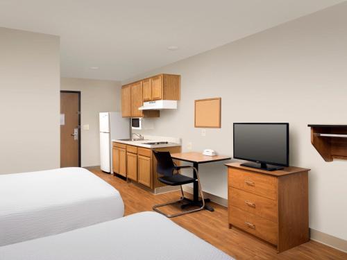 a hotel room with a bed and a desk with a television at Extended Stay America Select Suites - Indianapolis - Plainfield in Plainfield