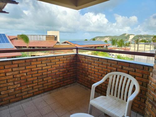 a white chair on a brick balcony with a view of the ocean at Pizzato Praia Hotel in Natal