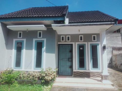 a small white house with a green door at D'House Homestay in Palembang
