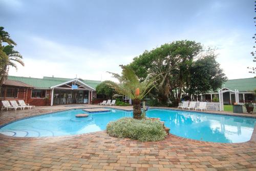a large swimming pool with a palm tree in the middle at Pine Lodge Resort in Port Elizabeth