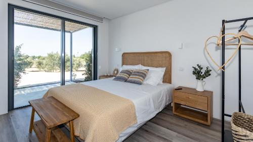 um quarto com uma cama e uma grande janela em Quinta da Amendoeira - Évora - The Farmhouse em Évora