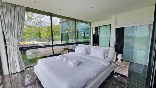 ein weißes Bett in einem Zimmer mit großen Fenstern in der Unterkunft Villa Obsidian, with staff, sea view and walk to Choeng Mon beach in Strand Choeng Mon