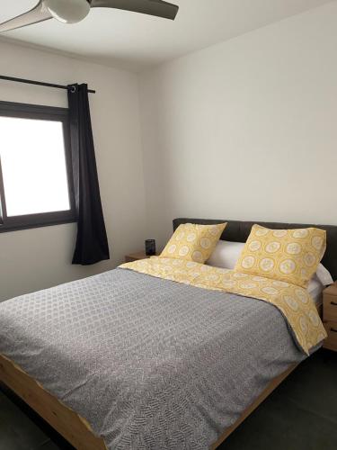 Un dormitorio con una cama con almohadas amarillas y una ventana en Appart Océan, en Étang-Salé les Bains