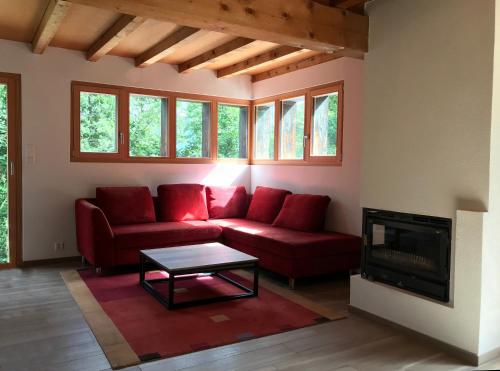 a living room with a red couch and a fireplace at Chalet près des bisses in Savièse